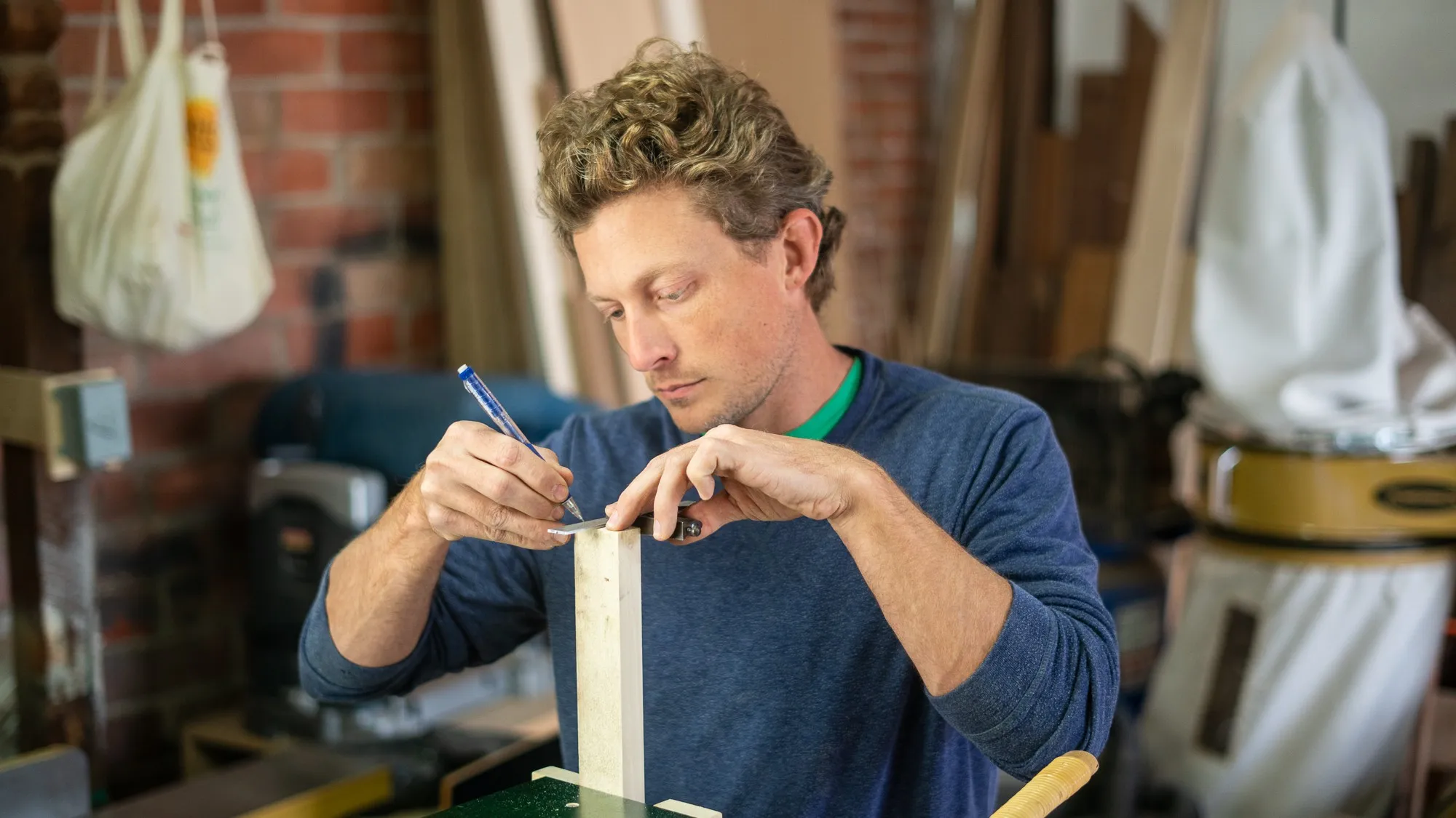 Bryan Ferris marking out a joint with a pencil at his bench, in his San Diego workshop.