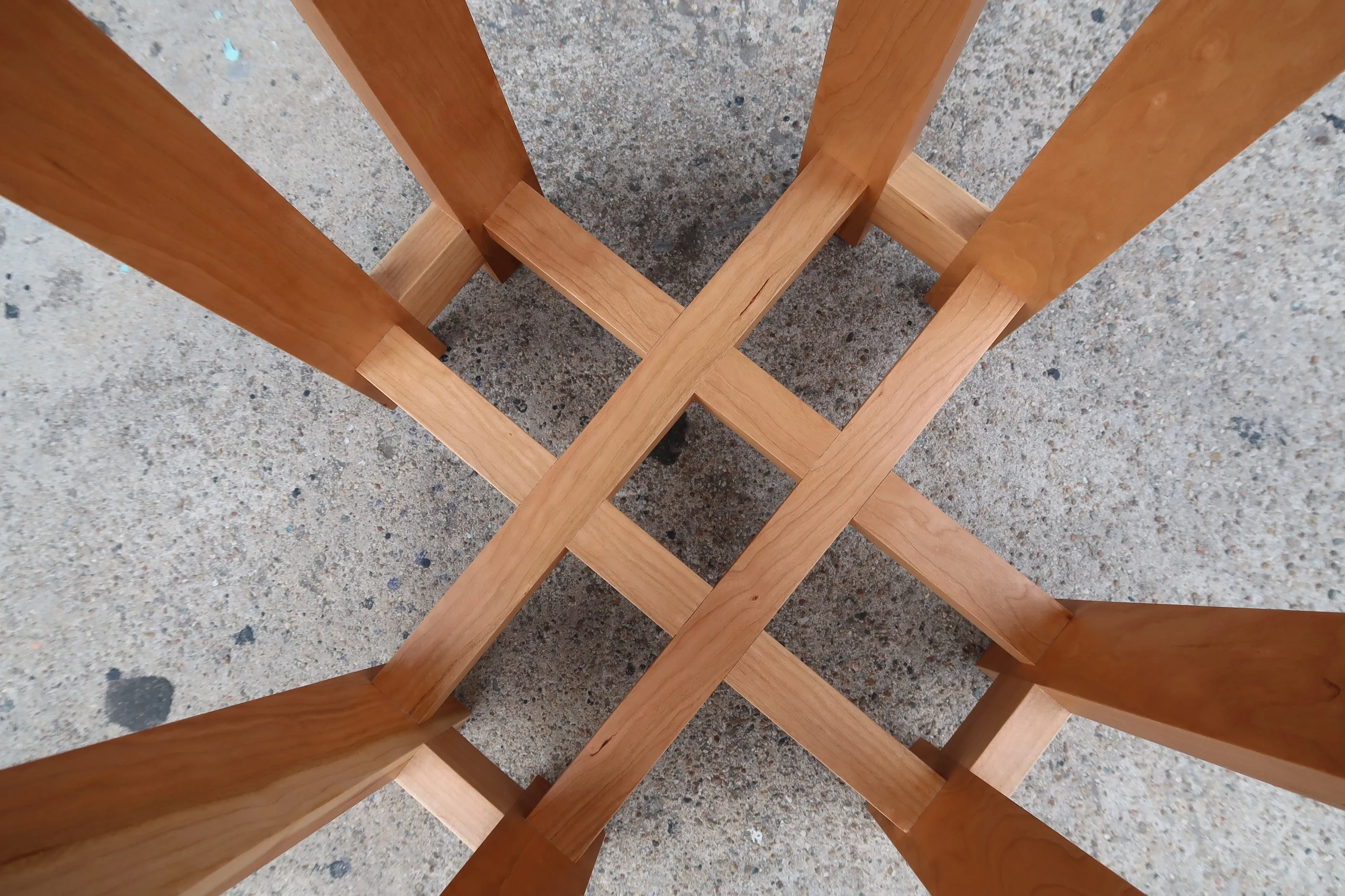 Looking straight down at the base of a cherry end table, where four stretchers cross and interlock in a half-lapped grid.